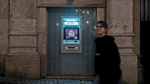 Una persona pasea junto a un cajero multibanco en Oporto.