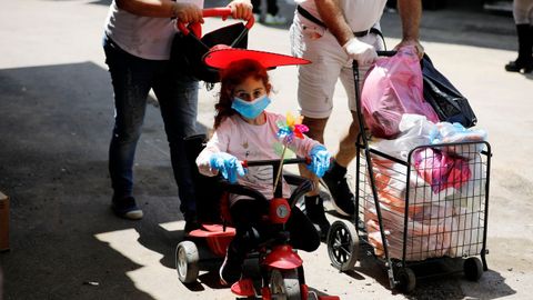 Una nia pasea con mascarilla y guantes cerca del mercado del Carmel, en Tel Aviv