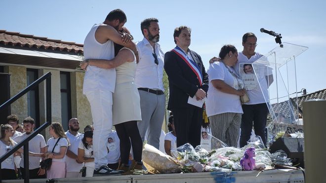 Los padres de Lyhanna, a la izquierda, se abrazan junto al alcalde de Fleurance, durante la marcha en homenaje a su hija.