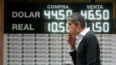 Un hombre camina frente a un tablero que anuncia las tasas de cambio del jueves en Buenos Aires