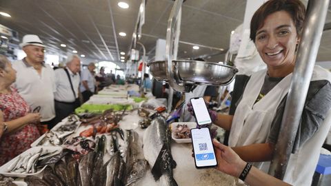 Una pescadera del mercado de Vilagarca muestra un telfono mvil con el cdigo del bono peixe, el que permite a los gallegos ahorrar en la compra de alimentos marinos frescos