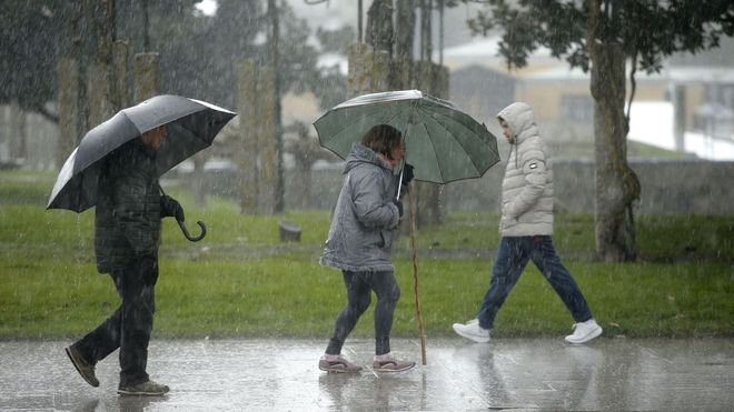 Varias personas caminan bajo la lluvia en Monforte. 