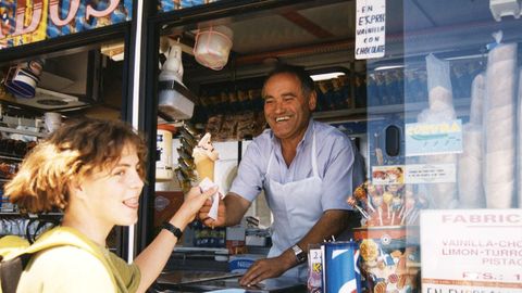 UN VENDEDOR DE HELADOS AMBULANTE SIRVE A UN JOVEN UN HELADO DE MAQUINA. ANA JUNQUERA. 15.7.98