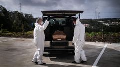 Trabajadores funerarios vestidos con trajes protectores miran un ata�d con el cuerpo de una mujer, que muri� de covid-19 en Amadora, en las afueras de Lisboa, Portugal.