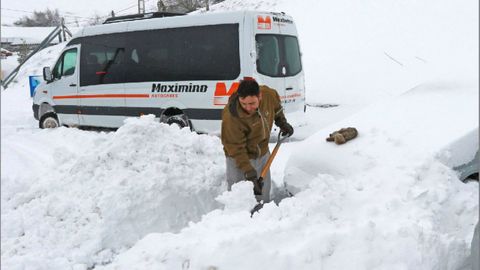 Un vecino del pueblo de Pajares (Asturias) trata de abrir con una pala el camino para sacar su veh�culo