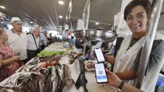 Una pescadera del mercado de Vilagarca muestra un telfono mvil con el cdigo del bono peixe, el que permite a los gallegos ahorrar en la compra de alimentos marinos frescos