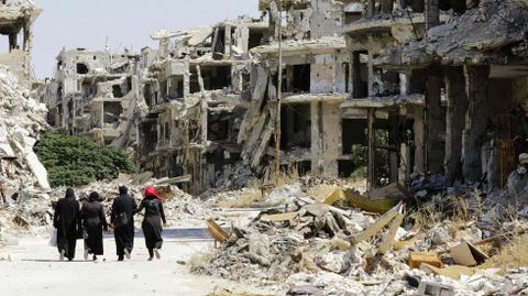 Mujeres pasan entre los edificios destruidos en el barrio de Jouret al Shiah, en Homs. 