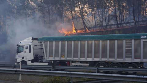 Un cami�n circula por la A8 en Luarca, ante las llamas del incendio