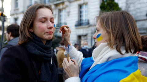 Una mujer llora mientras le pintan la cara con los colores de la bandera ucraniana durante una protesta contra la guerra frente a la embajada rusa en Pars.