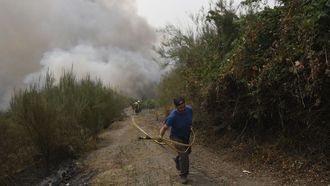Los vecinos, como este de la aldea de Centeais, trabajan para tratar de salvar sus casas de las llamas