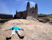 Una turista tomando el sol tumbada sobre la Pedra de Abalar, frente al santuario de A Barca.