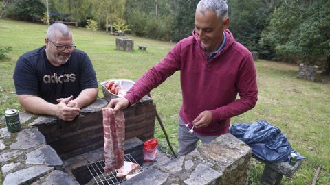 Suso (izquierda) y Chechu (derecha) preparan el churrasco para comer en la romera de Breamo, en Pontedeume.