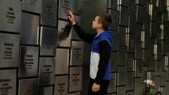 Un ni�o toca la placa con el nombre de su padre en el memorial por las v�ctimas de ejecuciones en Bucha, en la regi�n de Kiev