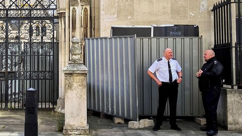 Dos agentes custodian el emplazamiento del nuevo grafiti de Bansky, que ha sido cubierto por barreras met�licas