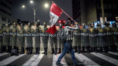 Un manifestante camina frente a una barrera de policías durante una protesta en Lima