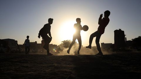 Un grupo de j�venes juegan al f�tbol al atardecer.