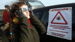 Una mujer, cuidando sus ojos con unas gafas homologadas, disfruta de un eclipse.