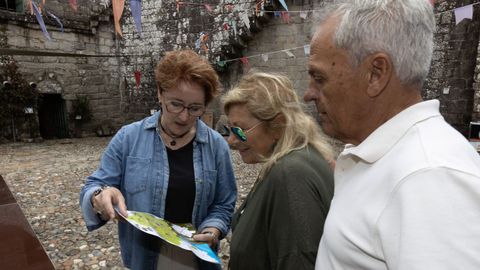 La t�cnica Mariv� Amigo muestra un mapa a dos turistas en el castillo de Vimianzo. 