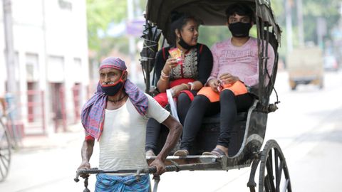 En Calcuta, un hombre ataviado con mascarilla tira de un rickshaws