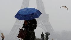 Una mujer sostiene un paraguas para protegerse de la nieve que cae cerca de la Torre Eiffel, en Par�s