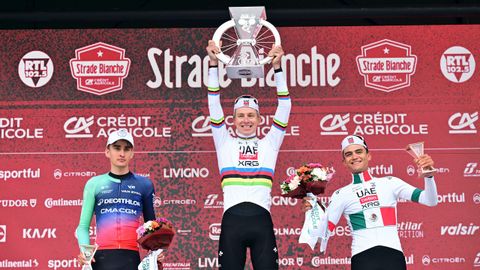 Pogacar levanta el t&iacute;tulo que le acredita como ganador de la Strade Bianche, flanqueado en el podio por Paul Seixas e Isaac del Toro.