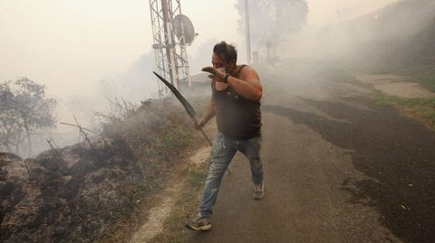 Un vecino de Frontn se protege del humo con un batefuegos en la mano