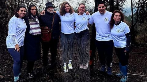 Cinco de los integrantes del equipo de fitboxing santiagu�s Toxo Box junto con Paula y Pablo Rodr�guez en el bosque de Ridimoas, donde pudieron ver nuevos brotes en medio de las cenizas (como el que protege un alambre en la foto) y conocer los planes que tiene la asociaci�n para la recuperaci�n del terreno ardido.