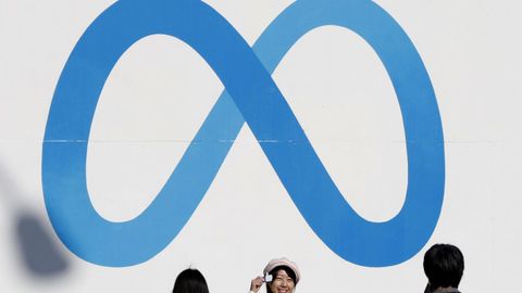 Personas ante un cartel con el anagrama de Meta, matriz de Facebook, Instagram y WhatsApp.