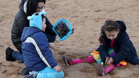La madre de Yago, Marta L�zaro, intenta comunicarse a trav�s de un ordenador con su hijo, que padece s�ndrome de Angelman, en la playa del Arbeyal de Gij�n donde sus hijos, con disfraces infantiles de carnaval, juegan con la arena de la playa