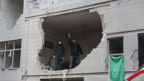 Una pareja comprueba desde el sal�n de su casa los da�os que los bombardeos han hecho en su vivienda del sur de Teher�n. 