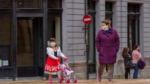 Una madre junto a su hija paseando un carrito de mu�ecas, en Oviedo