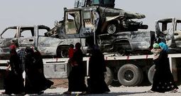 En su huida hacia el Kurdist�n, desplazados iraqu�es pasan ante restos de veh�culos militares en Al Hamdaniya. 