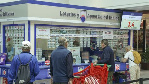 Clientes en la administraci�n de loter�as de Alcampo Ferrol. Tras la ventanilla est�n la due�a, Mar�a Luisa Cores, y una de las empleadas, Paula Testa.