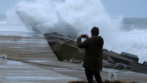 Un hombre toma im�genes de las olas este domingo en la playa de San Juan de Nieva en una jornada marcada por fuertes rachas de viento
