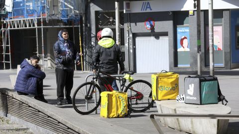 Repartidores de Glovo esperan a que los llamen descansando en la plaza Roxa, el mismo da del 2020 que se decretaba el estado de alarma.