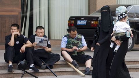 Mujeres de la etnia uigur pasan por delante de polic�as chinos en la ciudad de Urumqi, en la provincia de Xinjiang