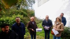 Vecinos junto a uno de los edificios que se encuentra rodeado por la maleza. 