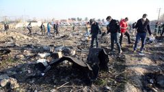 Agentes de emergencias inspeccionan los restos del avi�n derribado poco despues de su despegue en Teher�n.