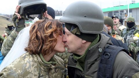 Los miembros de las Fuerzas de Defensa Territorial de Ucrania, Lesia Ivashchenko y Valerii Fylymonov, se besan en su boda durante el conflicto Ucrania-Rusia, en un puesto de control en Kiev, Ucrania.