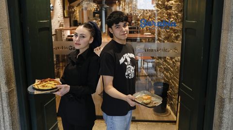 Kate y Yoel muestran el que ya se ha convertido en el plato estrella de Sarabia Gastrobar, su cachopo, y uno de sus postres. El negocio abre todos los días (salvo miércoles) de 9 a 23.30 horas, y los viernes y sábados hasta las 24 horas. El nombre de Sarabia hace alusión al clima santiagués, que su dueña adora.
