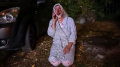 Una mujer en pijama y herida al tener que salir de su casa en Kiev tras el bombardeo de un bloque de apartamentos