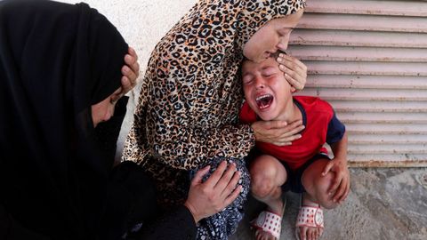 Un niño gazatí llora la muerte de su hermana, alcanzada por bombas israelíes cuando esperaban a recibir alimentos, mientras su madre trata de consolarlo
