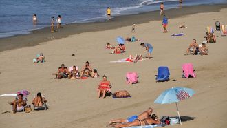 Varias personas toman el sol en la playa de Salinas (Asturias),