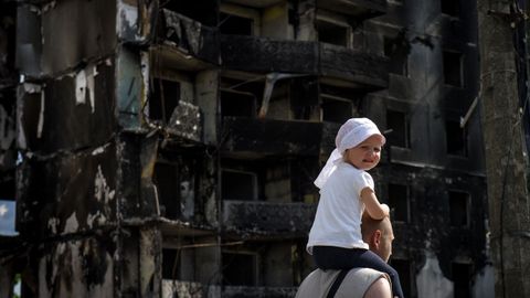 Un hombre camina con una ni�a a hombros ante un edificio destruido en Borodianka, en la regi�n de Kiev
