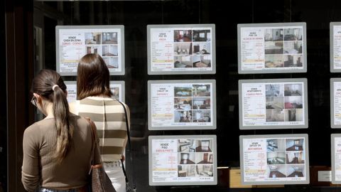 J�venes consultan la fachada de una inmobiliaria en Santiago.