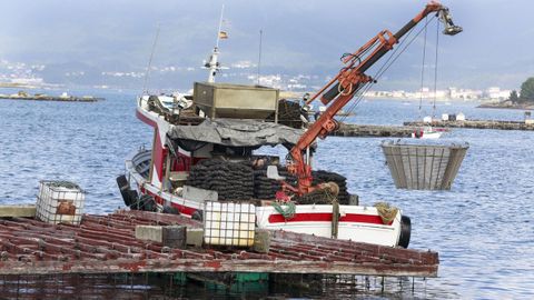 Un barco mejillonero al lado de una batea en Arousa (imagen de archivo)