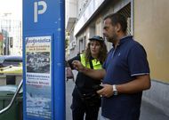 Una empleada de la ORA ayuda a un conductor a obtener su tique de aparcamiento. 
