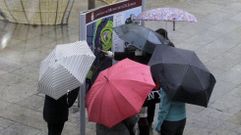 Turistas con paraguas, estas pasadas Navidades junto a un panel informativo en el centro de Monforte