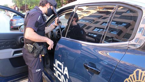 Un agente de la Polica Nacional junto a un coche patrulla, en una imagen de archivo.