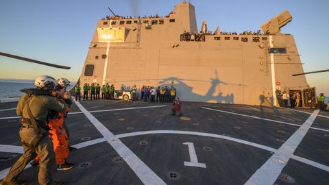 Una vista general de la astronauta de la NASA Christina Koch, especialista de la misi�n Artemis 2, siendo asistida para salir de la cubierta de vuelo despu�s de llegar a bordo del John P. Murtha.